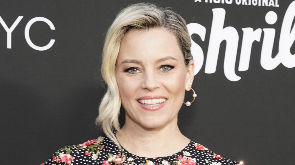 Elizabeth Banks un negro, blanco-polka punteado, vestido floral, posando con una sonrisa en un evento