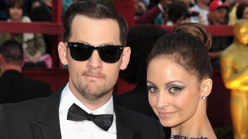 Joel Madden con un esmoquin negro y gafas de sol, Nicole Richie con un vestido plateado sonriendo en los Oscar de 2010