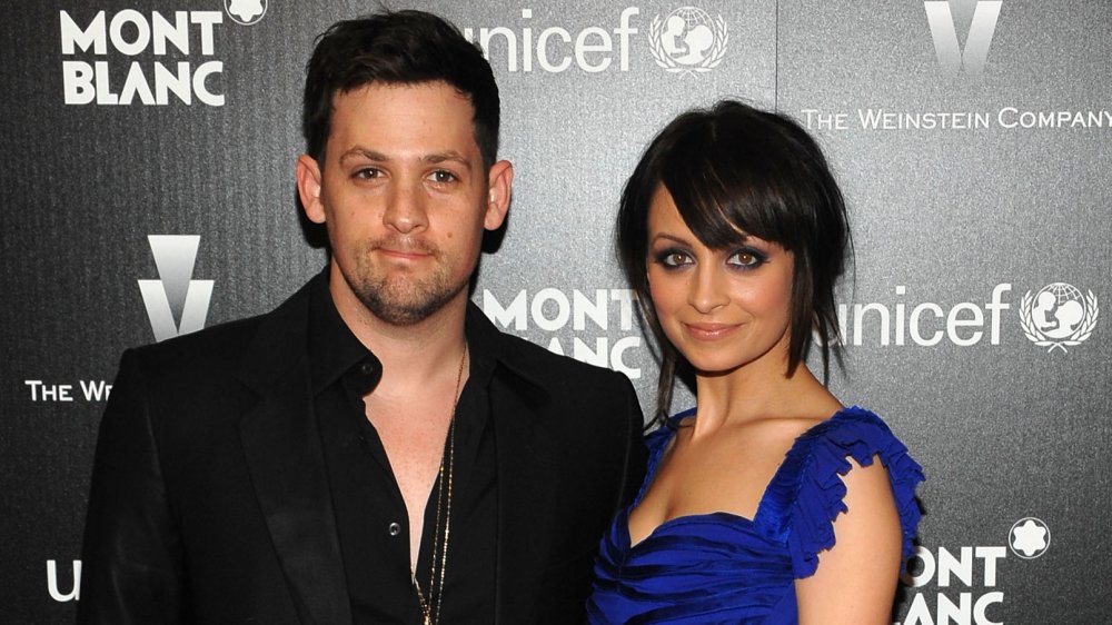 Joel Madden con un blazer negro y camisa abotonada abierta, Nicole Richie con un vestido azul