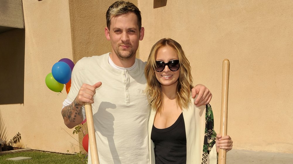 Joel Madden, Nicole Richie sosteniendo palas y sonriendo afuera