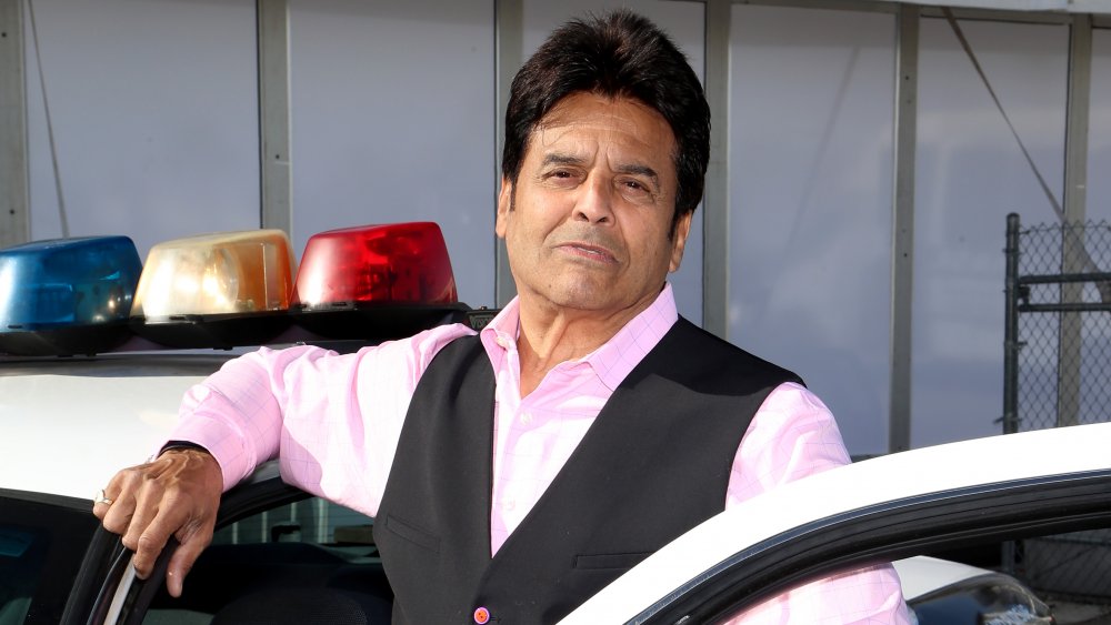 Erik Estrada posando junto a un crucero de la policía 