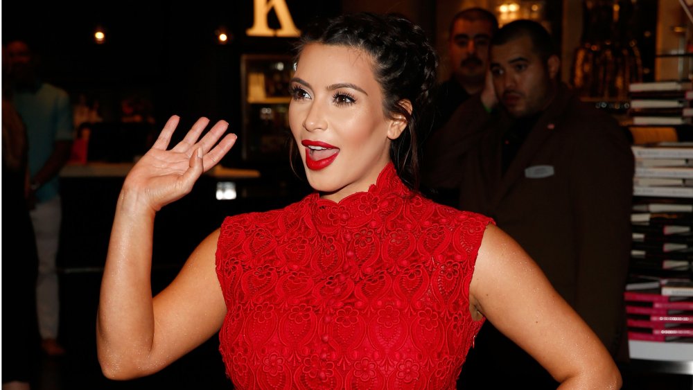 Kim Kardashian con un vestido rojo, saludando