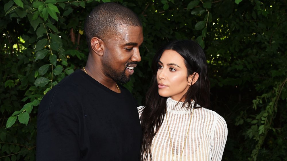 Kanye West y Kim Kardashian frente a la vegetación, mirándose unos a otros