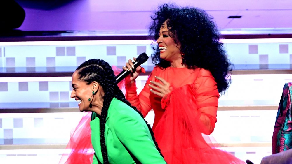 Tracee Ellis Ross con traje verde, Diana Ross con un vestido rojo, ambos riendo en el escenario en los Grammy 2019