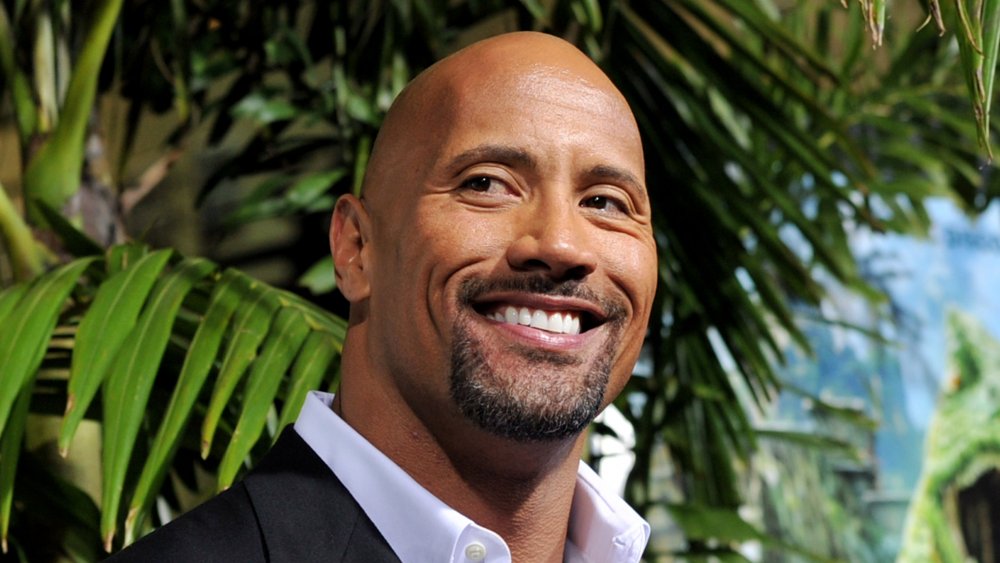 Dwayne 'The Rock' Johnson sonriendo frente a la palmera