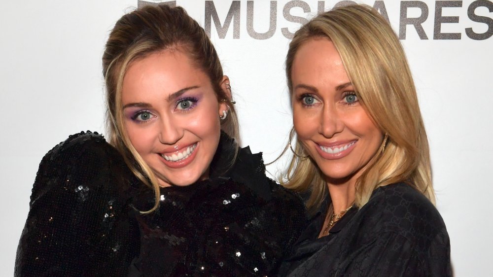 Miley Cyrus y Tish Cyrus, ambos vestidos de negro y sonriendo