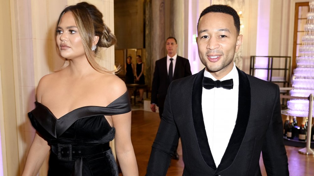 Chrissy Teigen y John Legend caminando juntos en un evento formal