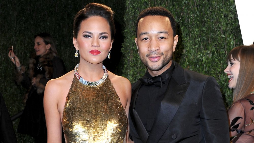 Chrissy Teigen en un vestido de oro de pie con John Legend