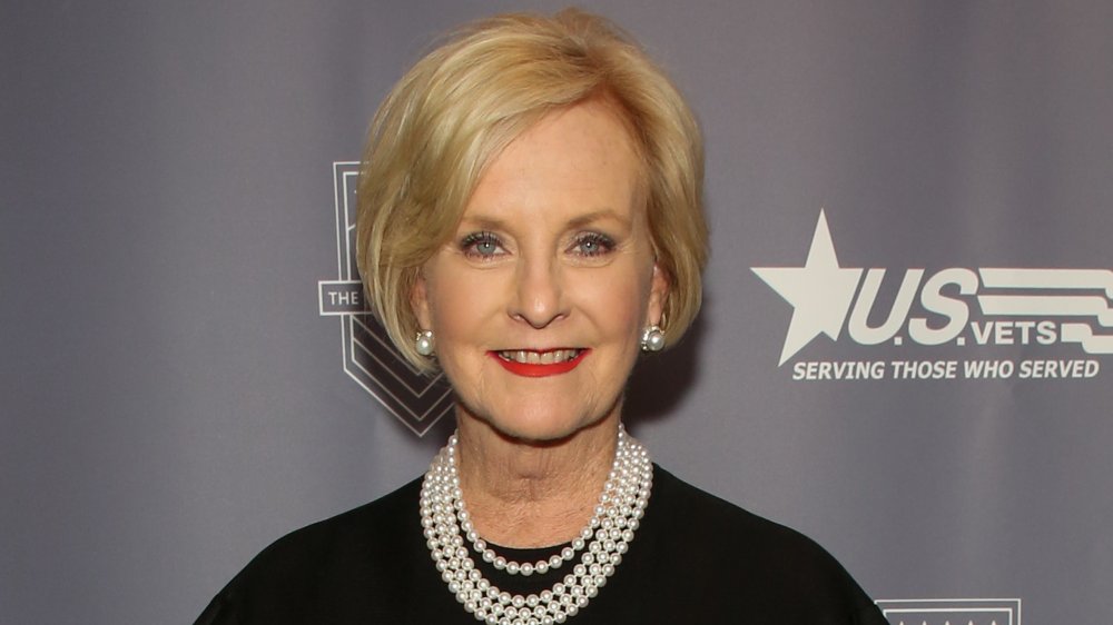 Cindy McCain con un vestido negro y un collar de perlas, sonriendo en un evento de veteranos