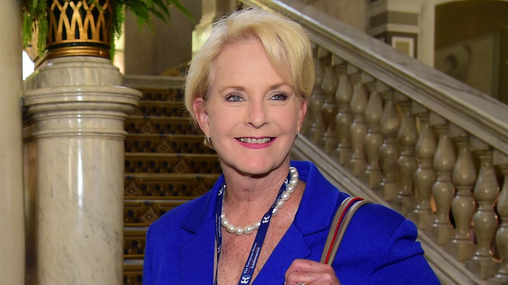 Cindy McCain sonriendo con un vestido azul y perlas