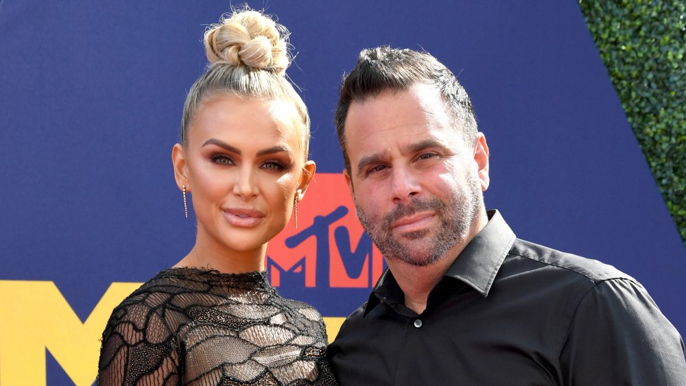 Lala Kent con un vestido negro con el pelo en un moño alto, Randall Emmett en un botón negro