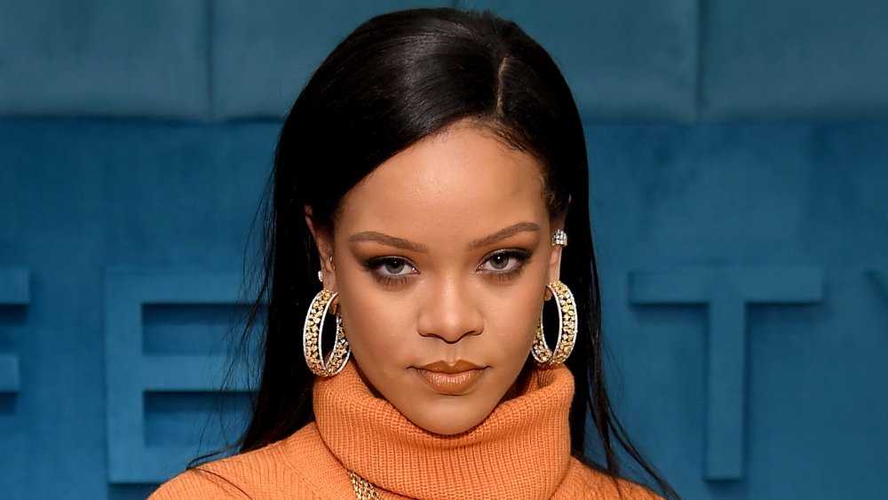 Rihanna con un vestido de cuello de tortuga naranja, posando con una expresión seria