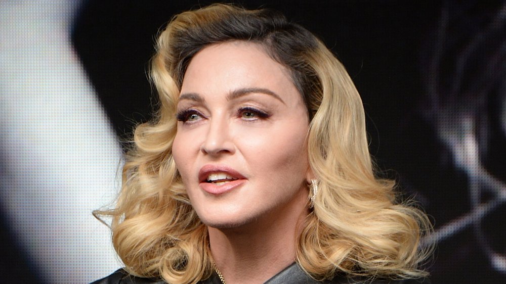 Madonna con un traje de cuero negro, hablando mientras mira hacia un lado