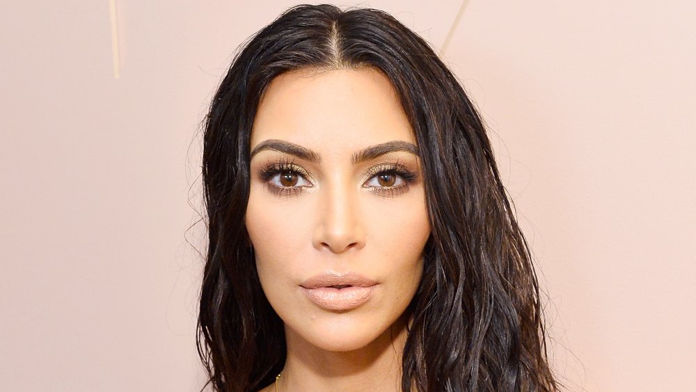 Kim Kardashian con un vestido blanco y un look de pelo mojado, posando con una expresión sorprendida