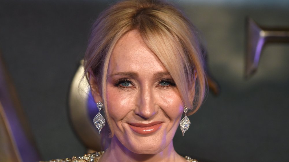 J.K. Rowling con un vestido brillante de oro, sonriendo con el pelo recogido