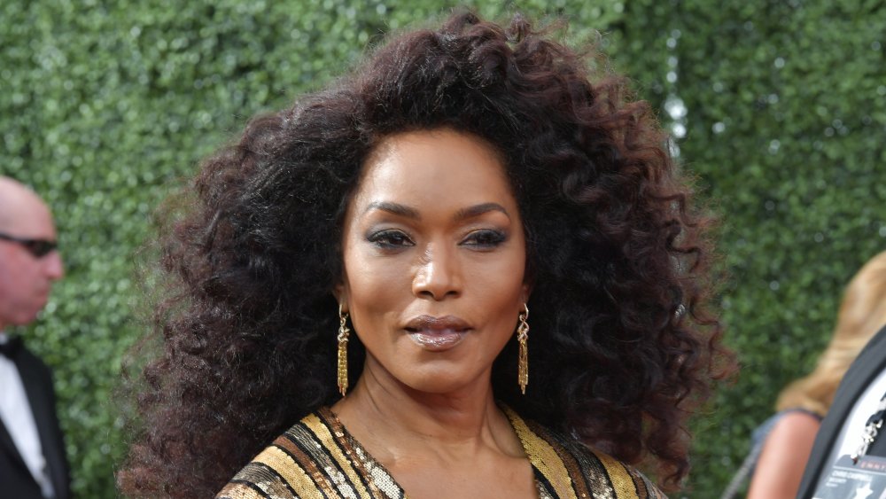 Angela Bassett en un vestido a rayas de oro brillante, posando con una expresión seria