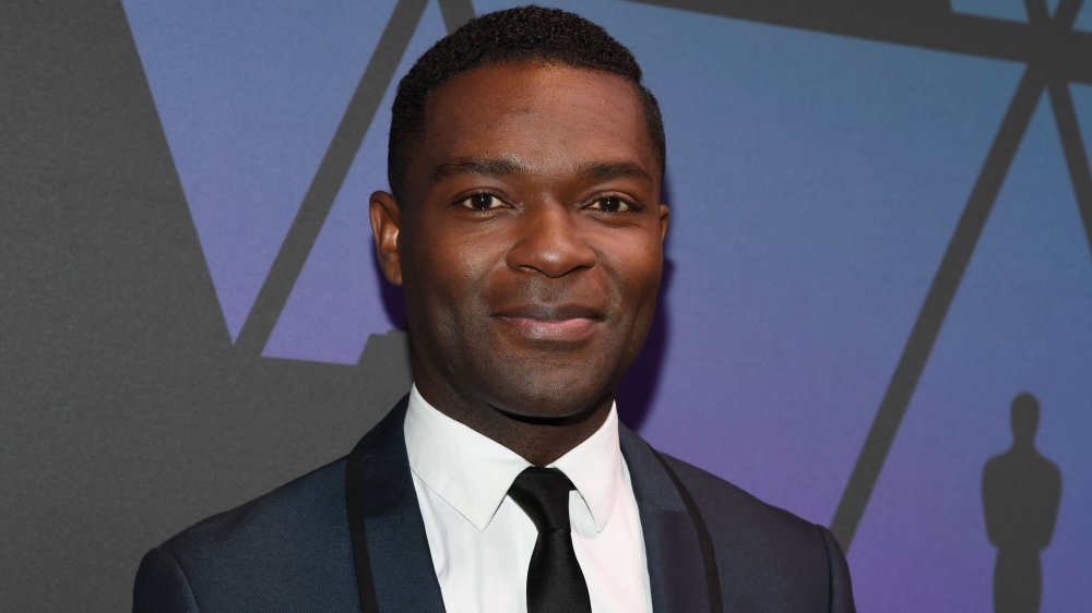 David Oyelowo en un traje azul oscuro, forrado en negro, posando con una pequeña sonrisa en los Oscar