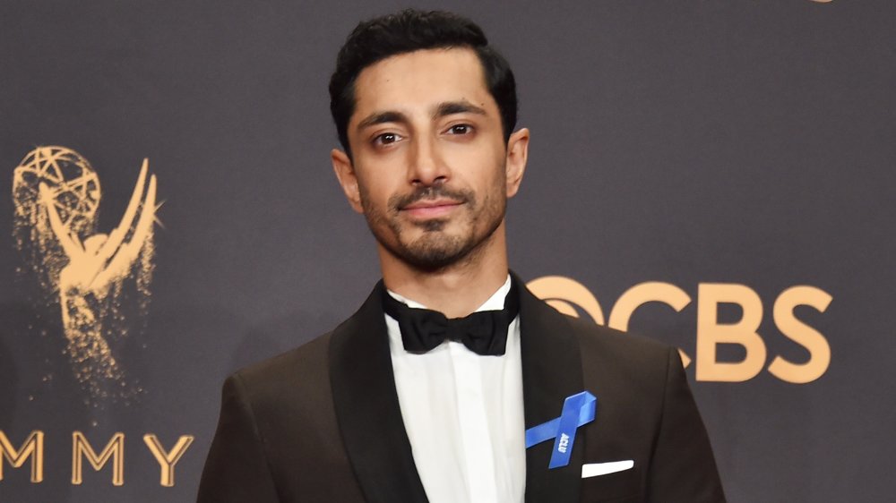 Riz Ahmed con traje negro y pajarita, posando con su Emmy