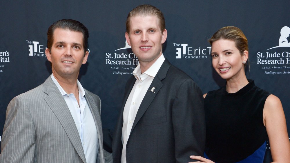 Donald Trump Jr., Eric Trump e Ivanka Trump posando frente a la pared