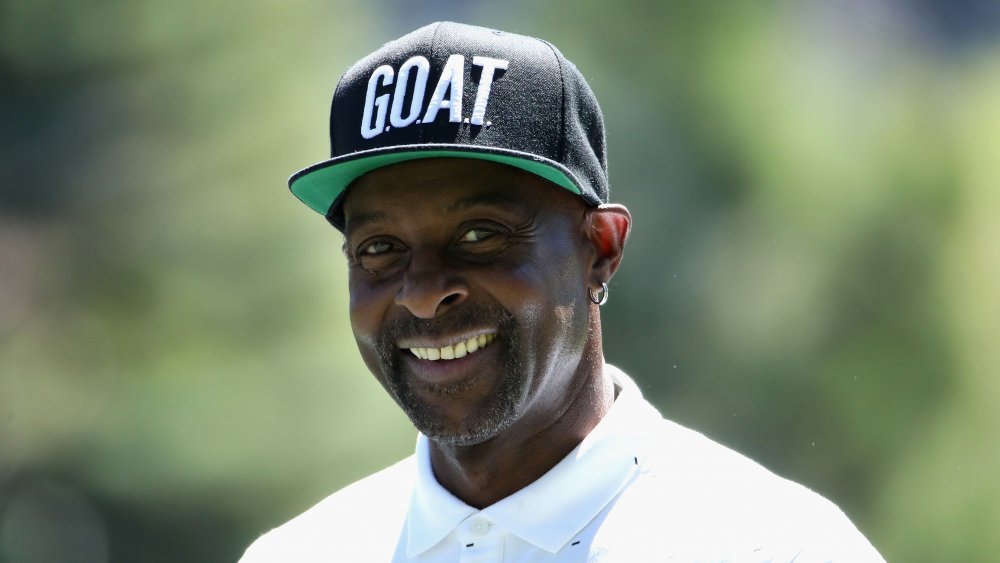 Jerry Rice sonriendo en un polo blanco y sombrero NEGRO GOAT