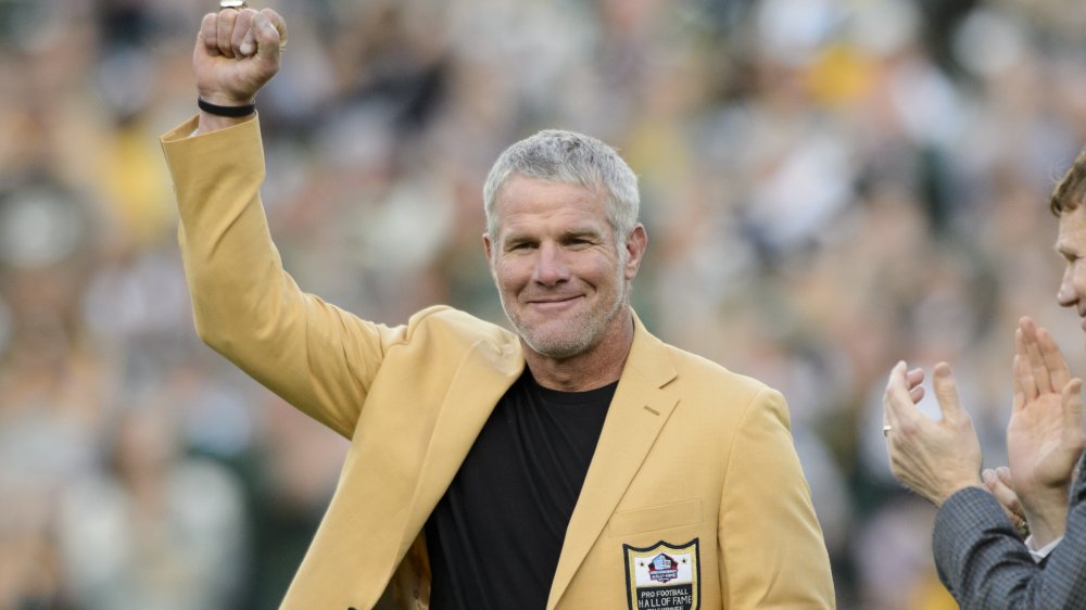 Brett Favre en un blazer amarillo del Salón de la Fama, posando con el puño en el aire en un juego