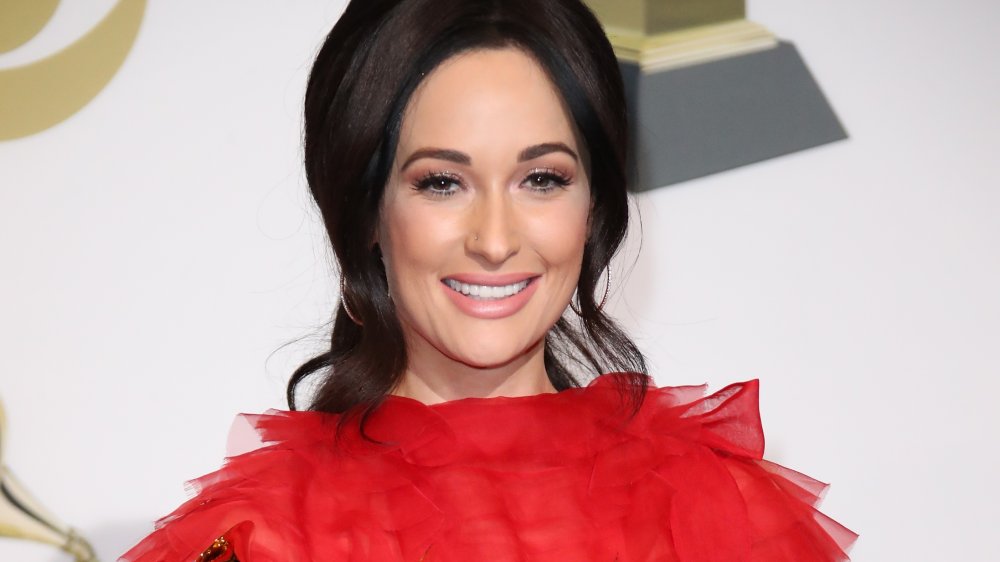 Kacey Musgraves en un vestido rojo y el pelo tirado hacia atrás