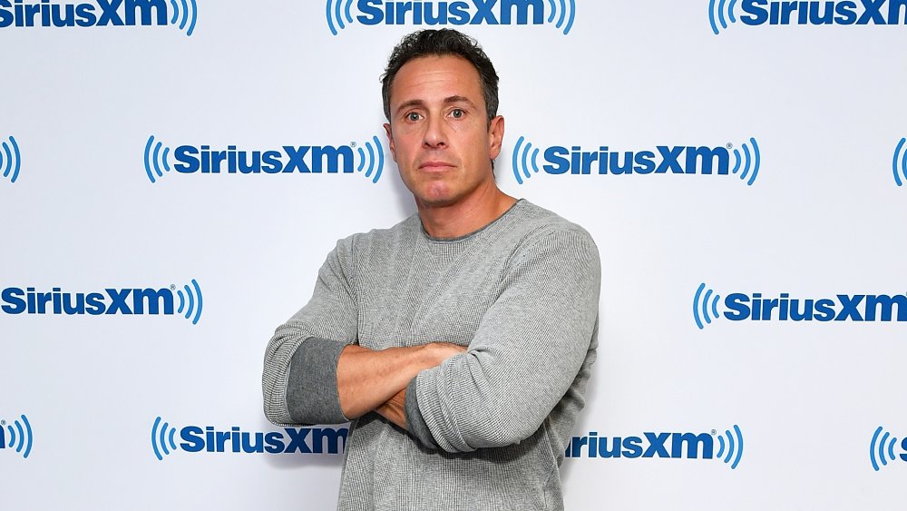 Chris Cuomo, con los brazos cruzados, frente a la pared de SiriusXM