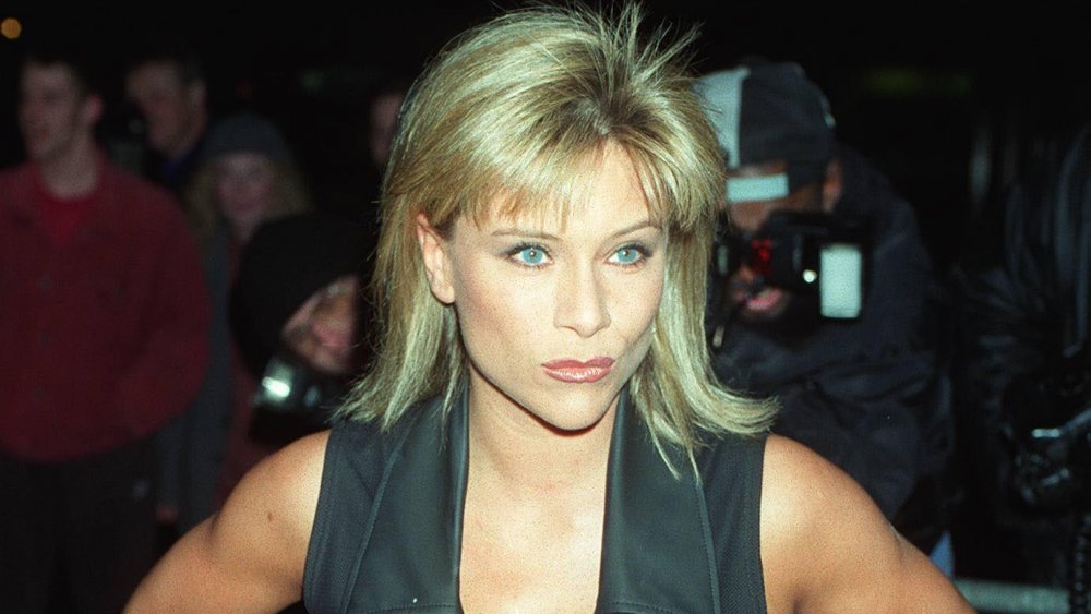 Samantha Fox con un traje negro, posando con una sonrisa mientras está rodeada de fotógrafos a mediados de los 90