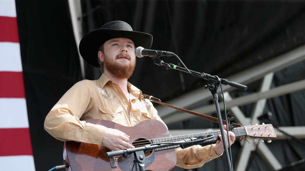 Colter Wall en sombrero de vaquero y guitarra en el escenario