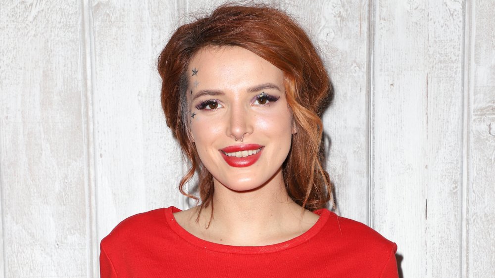 Bella Thorne con el pelo rojo tirado hacia atrás y los labios rojos