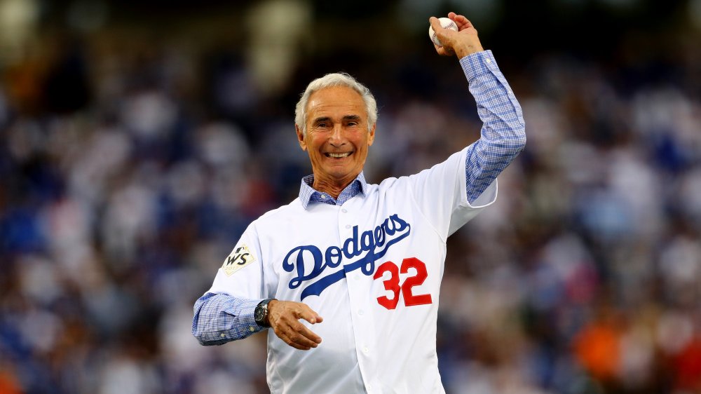 Un Sandy Koufax mayor sonriendo mientras lanza un lanzamiento