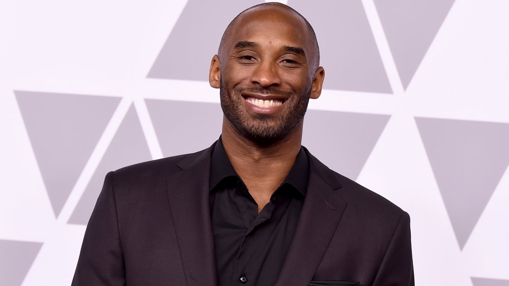 Kobe Bryant con un traje totalmente negro, sonriendo