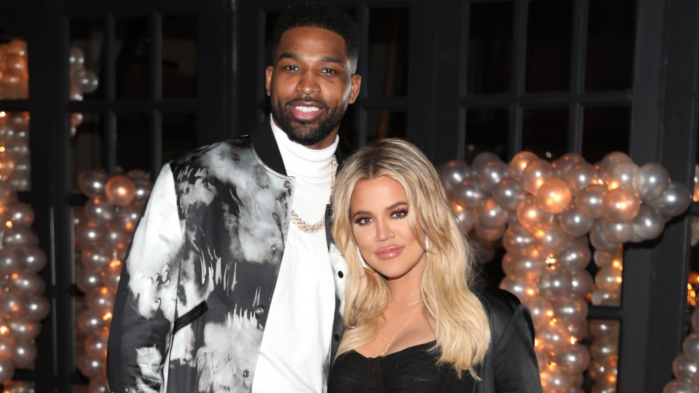 Tristan Thompson y Khloe Kardashian sonriendo juntos frente a un montón de globos