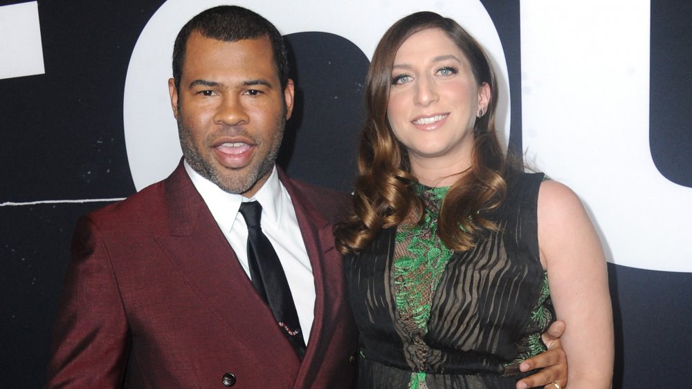 Jordan Peele en traje granate, Chelsea Peretti con un vestido verde y negro