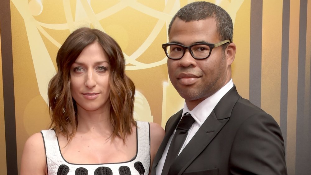 Chelsea Peretti con un vestido blanco y negro, Jordan Peele con traje y gafas negras