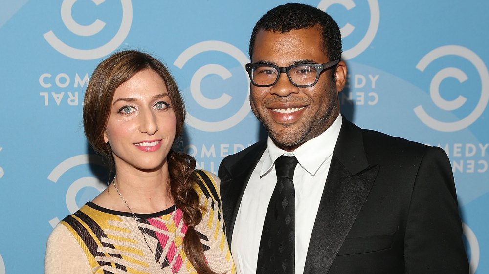 Chelsea Peretti con un vestido amarillo y negro, Jordan Peele con traje negro y gafas