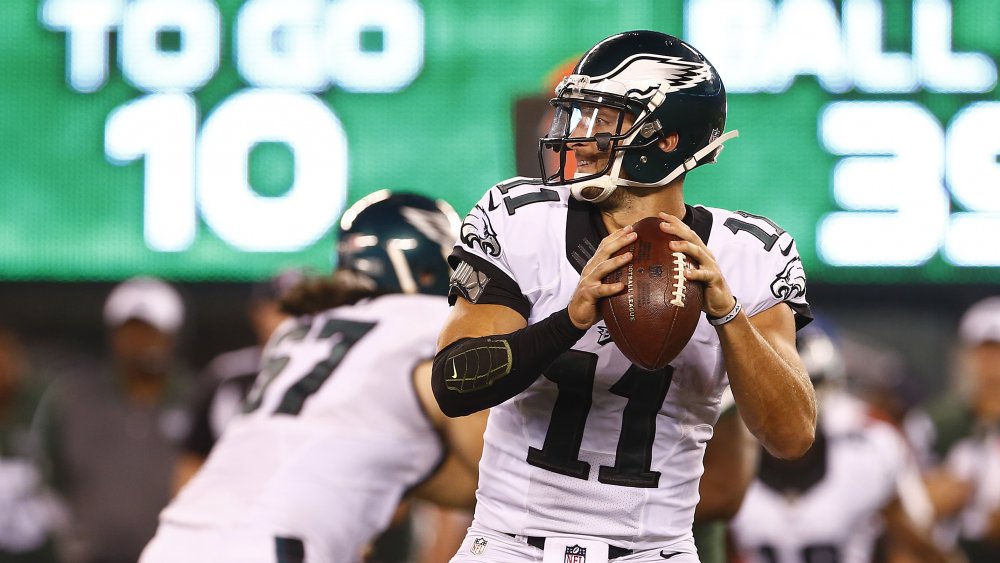 Tim Tebow a punto de lanzar un balón de fútbol con un uniforme de las Philadelphia Eagles