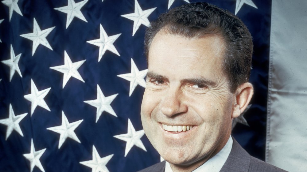 Richard Nixon sonriendo frente a la bandera de EE.UU.