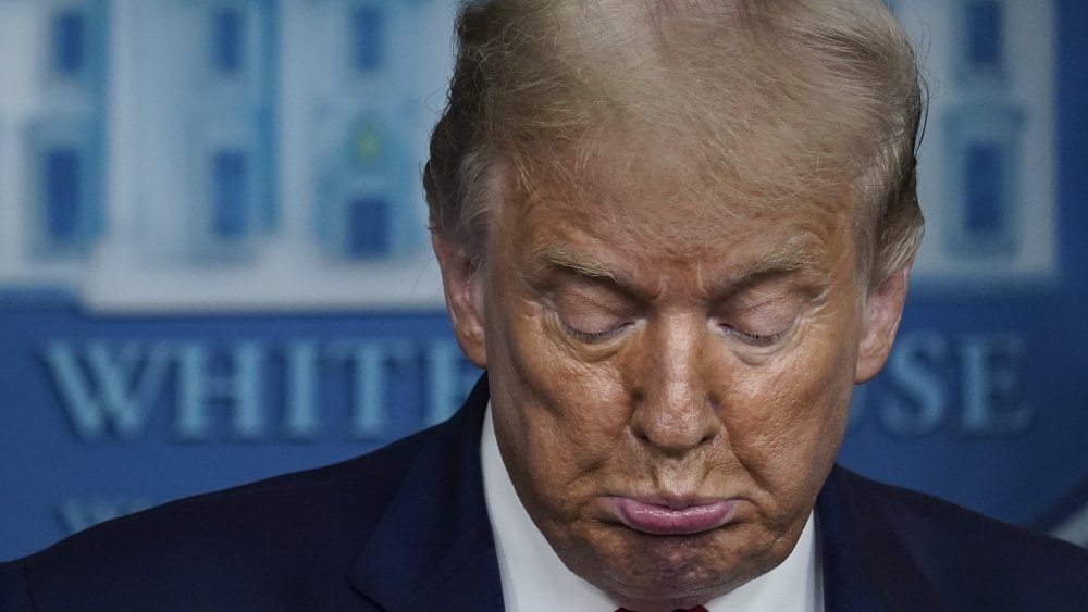 Donald Trump, labio inferior sobresaliendo, mirando hacia abajo