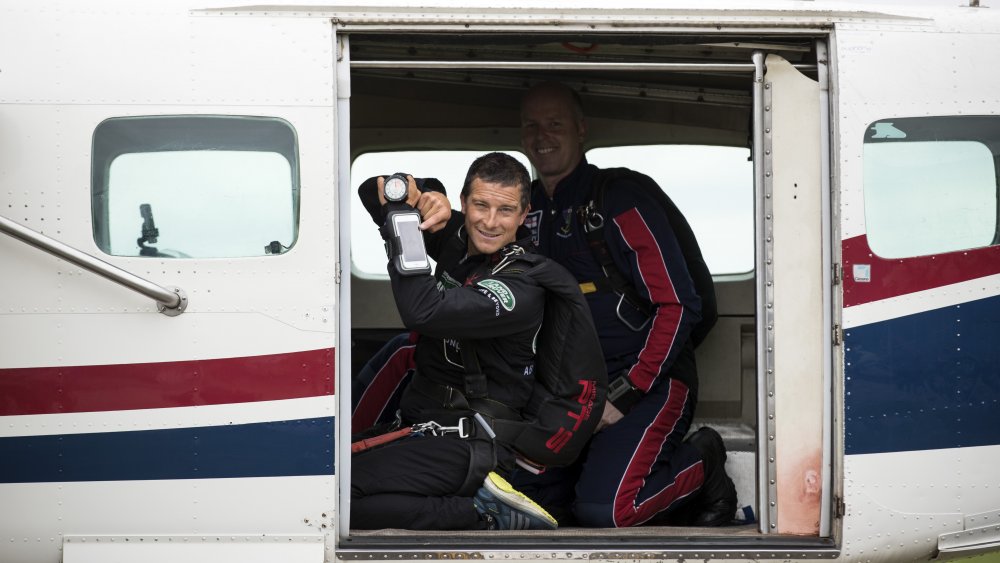 Oso Grylls en un avión, posando con su teléfono