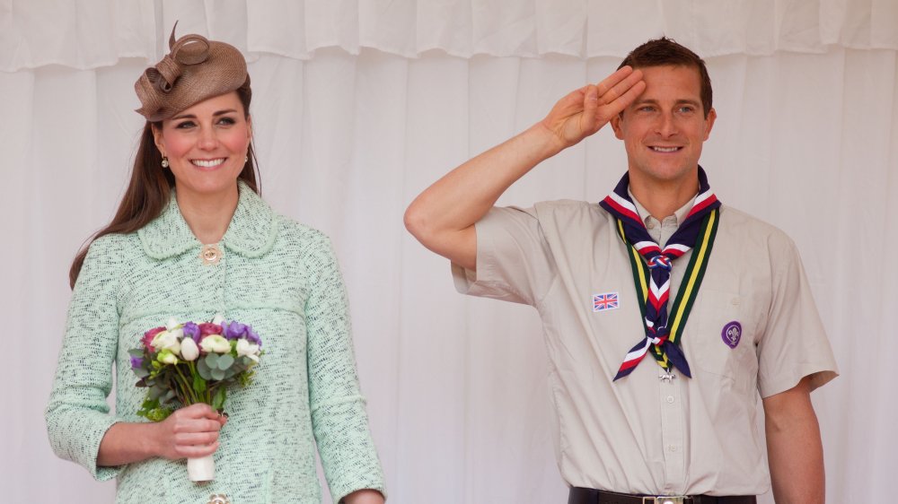 Bear Grylls saludando, de pie junto a Kate Middleton