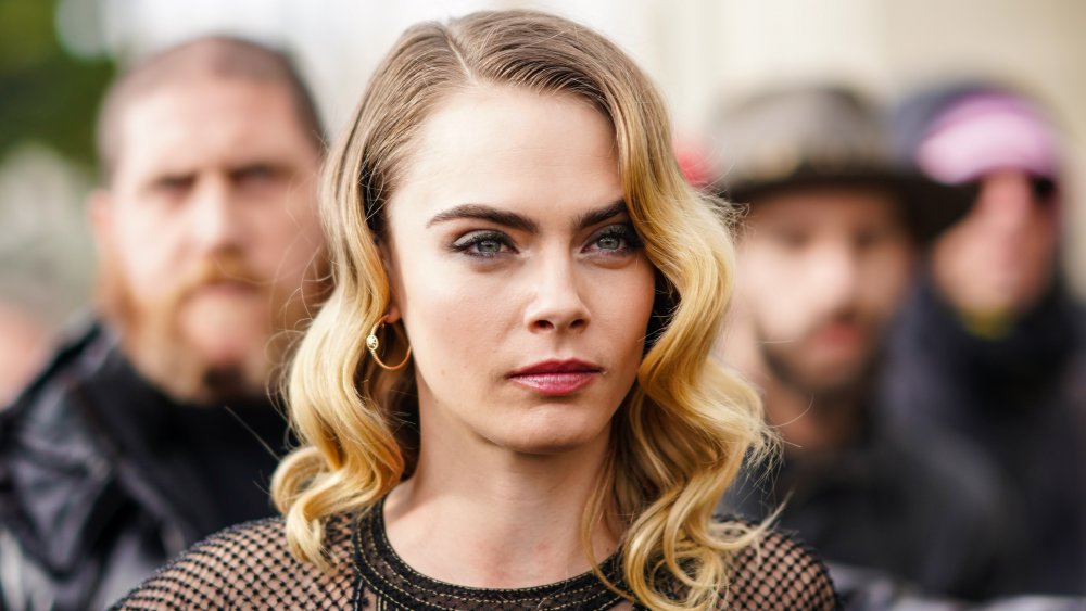 Cara Delevingne con el pelo rizado y una tapa de malla