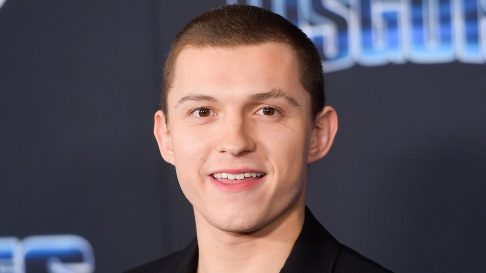 Tom Holland con un corte de zumbido, sonriendo en un estreno de película