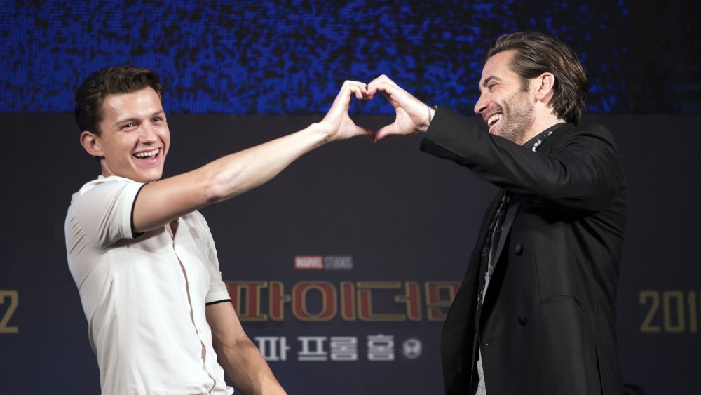 Tom Holland y Jake Gyllenhaal se ríen mientras forman un corazón con las manos en un evento de prensa de Spider-Man: Far From Home