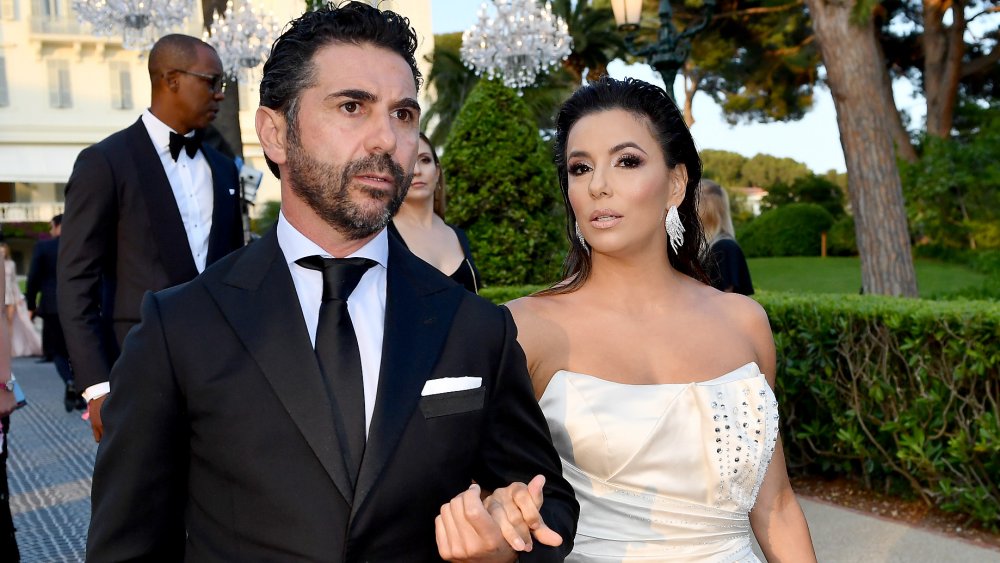 José Bastón y Eva Longoria caminando afuera, vestidos