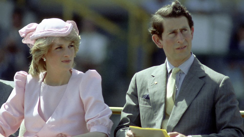 La princesa Diana y el príncipe Carlos, ambos mirando hacia un lado con una mueca