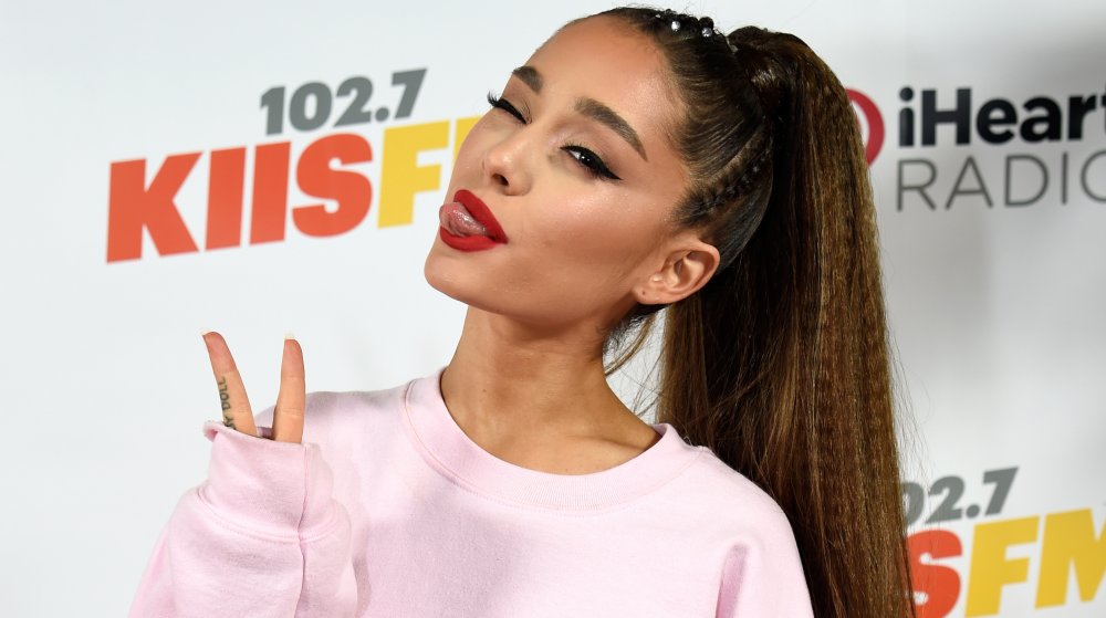 Ariana Grande con su cola de caballo de la firma, lanzando un cartel de paz