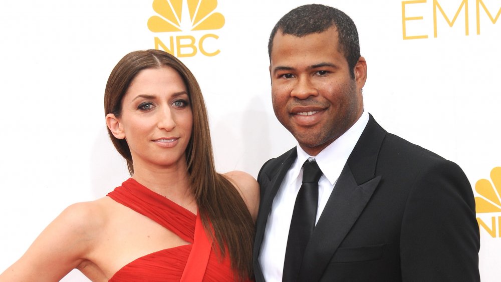 Chelsea Peretti con un vestido rojo, Jordan Peele con un traje negro, ambos sonriendo a los Emmy