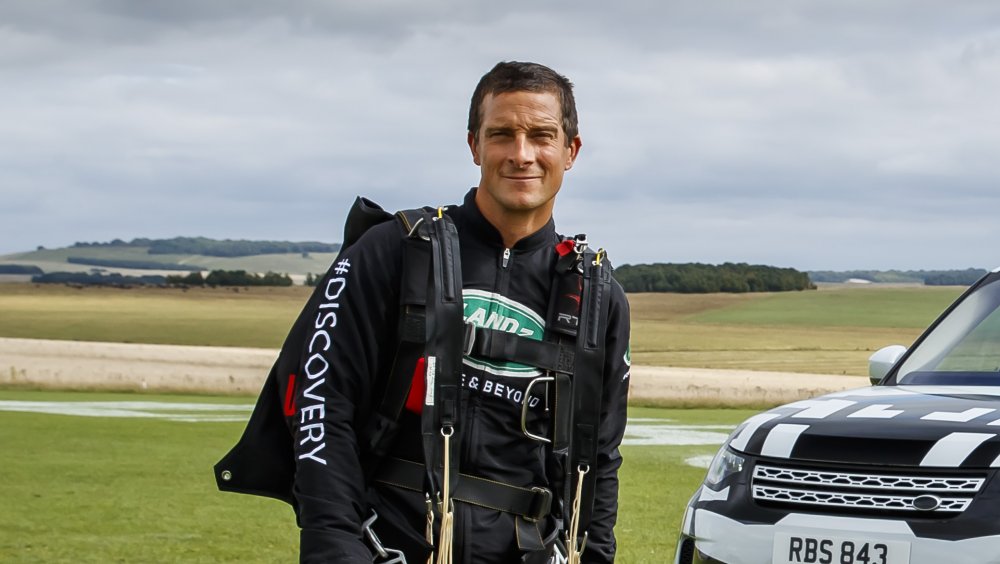 Bear Grylls en equipo al aire libre junto a un coche