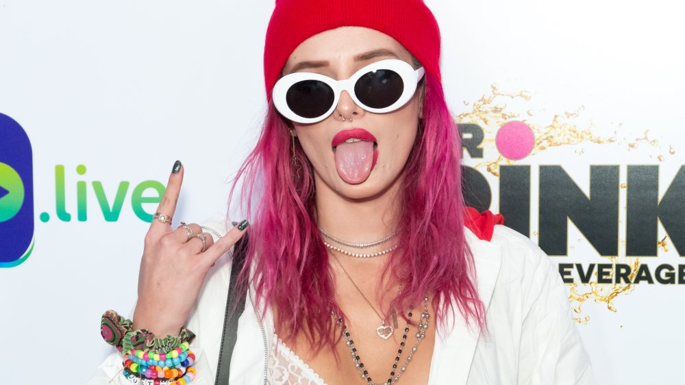 Bella Thorne en un gorro rojo y pelo rosado con gafas de sol blancas